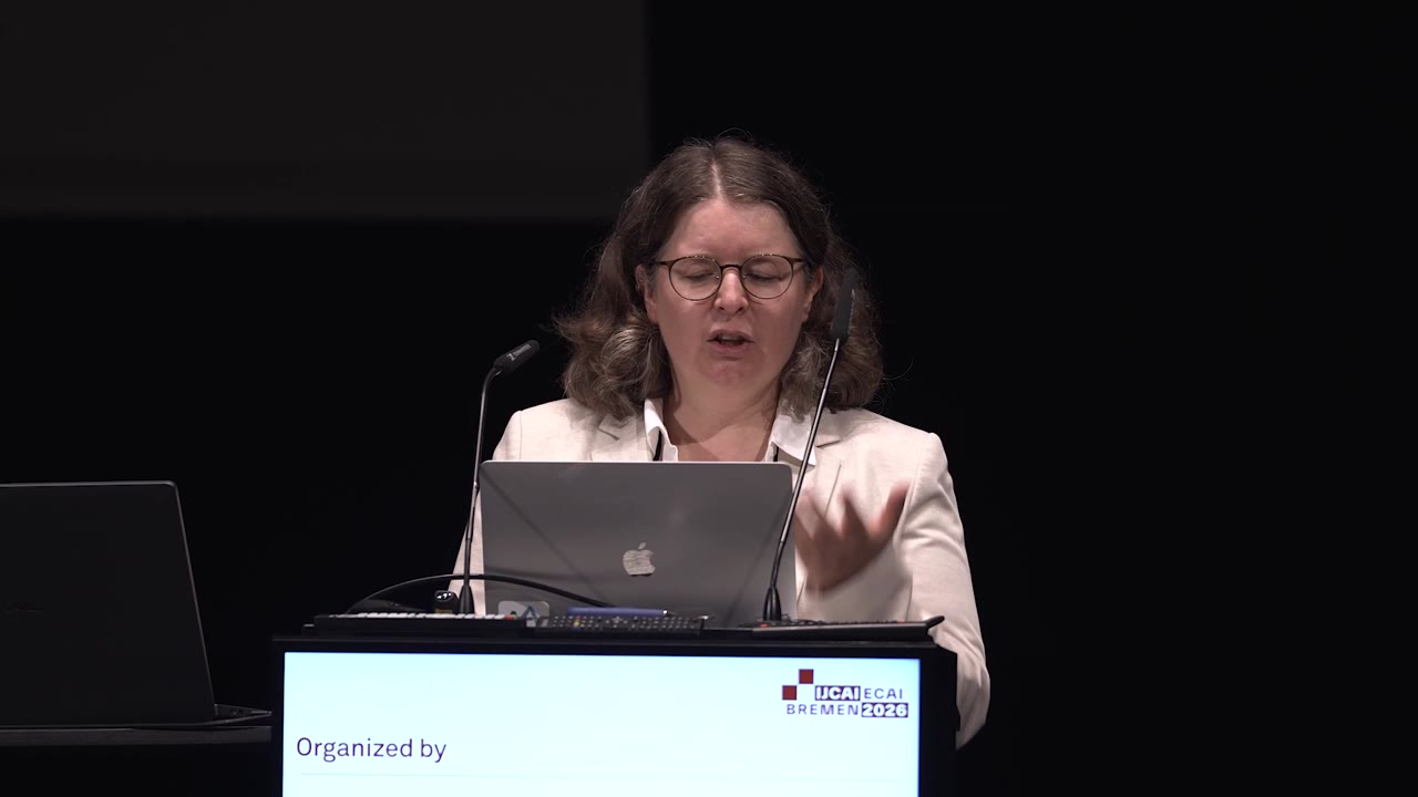 Barbara Plank speaking at the lectern on the IJCAI–ECAI 2026 stage in Bremen